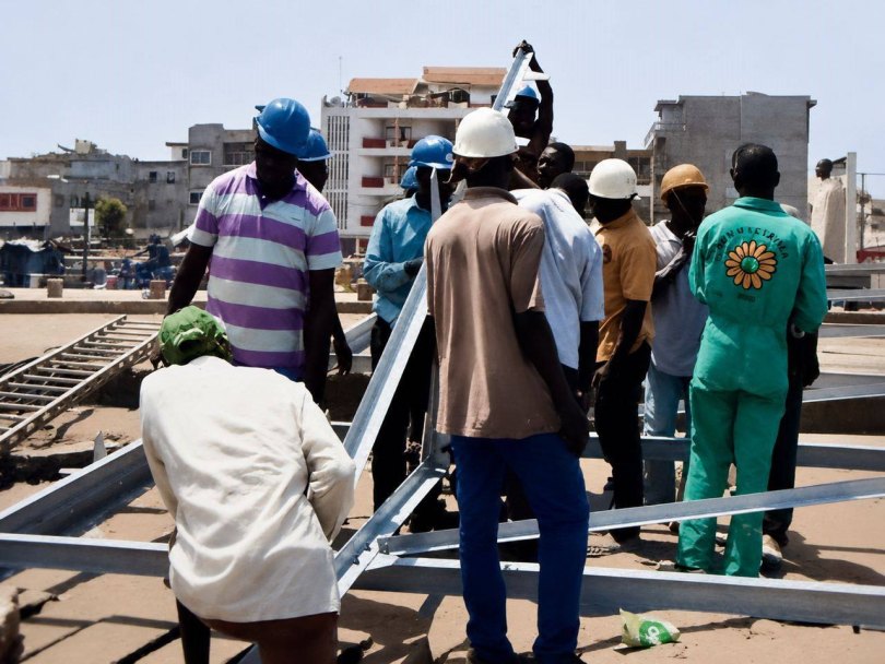 Ouvriers casqués rassemblés autour d'une structure métallique en cours d'assemblage sur un chantier